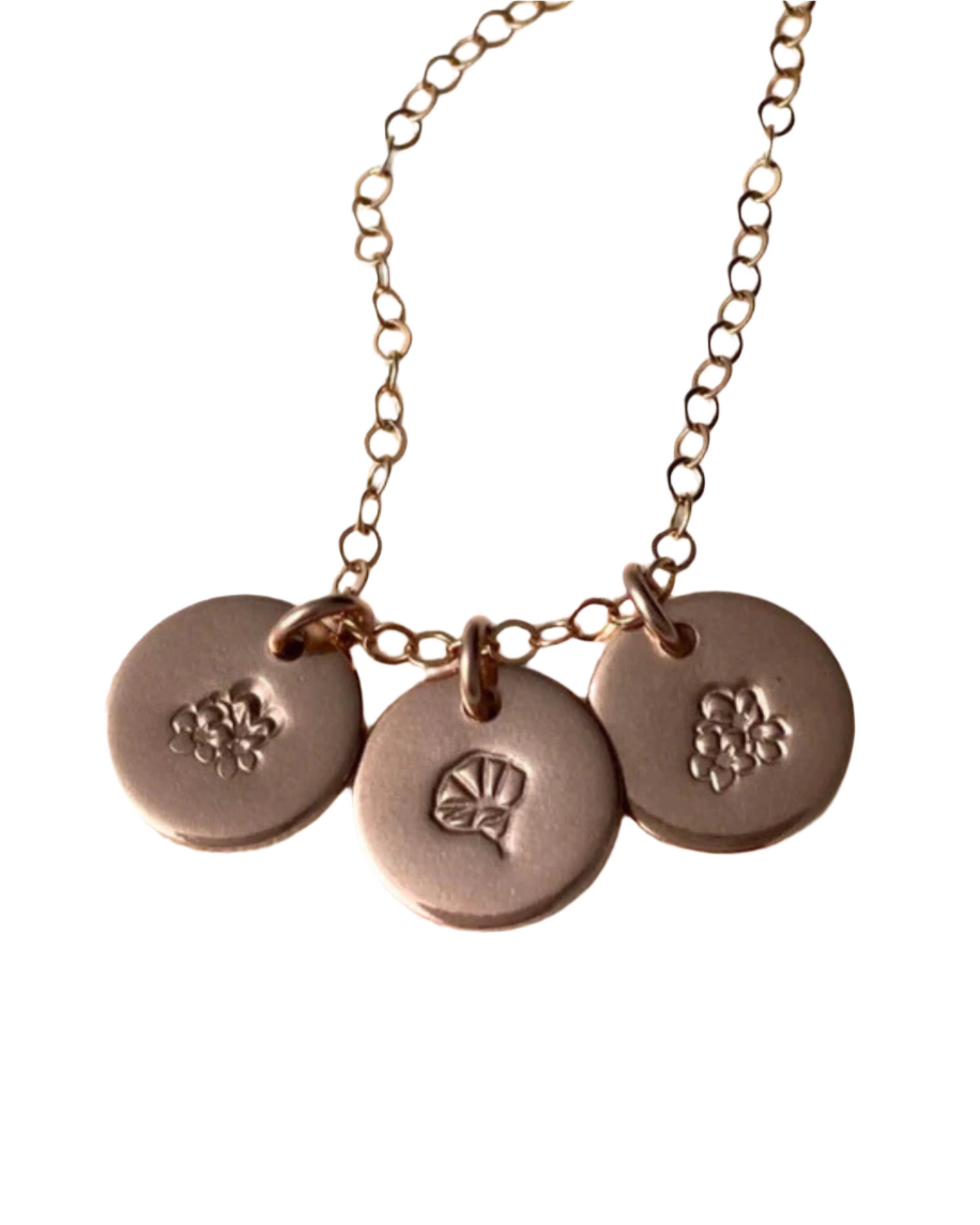 A necklace with three round metal discs attached to a chain, each engraved with a different floral design.