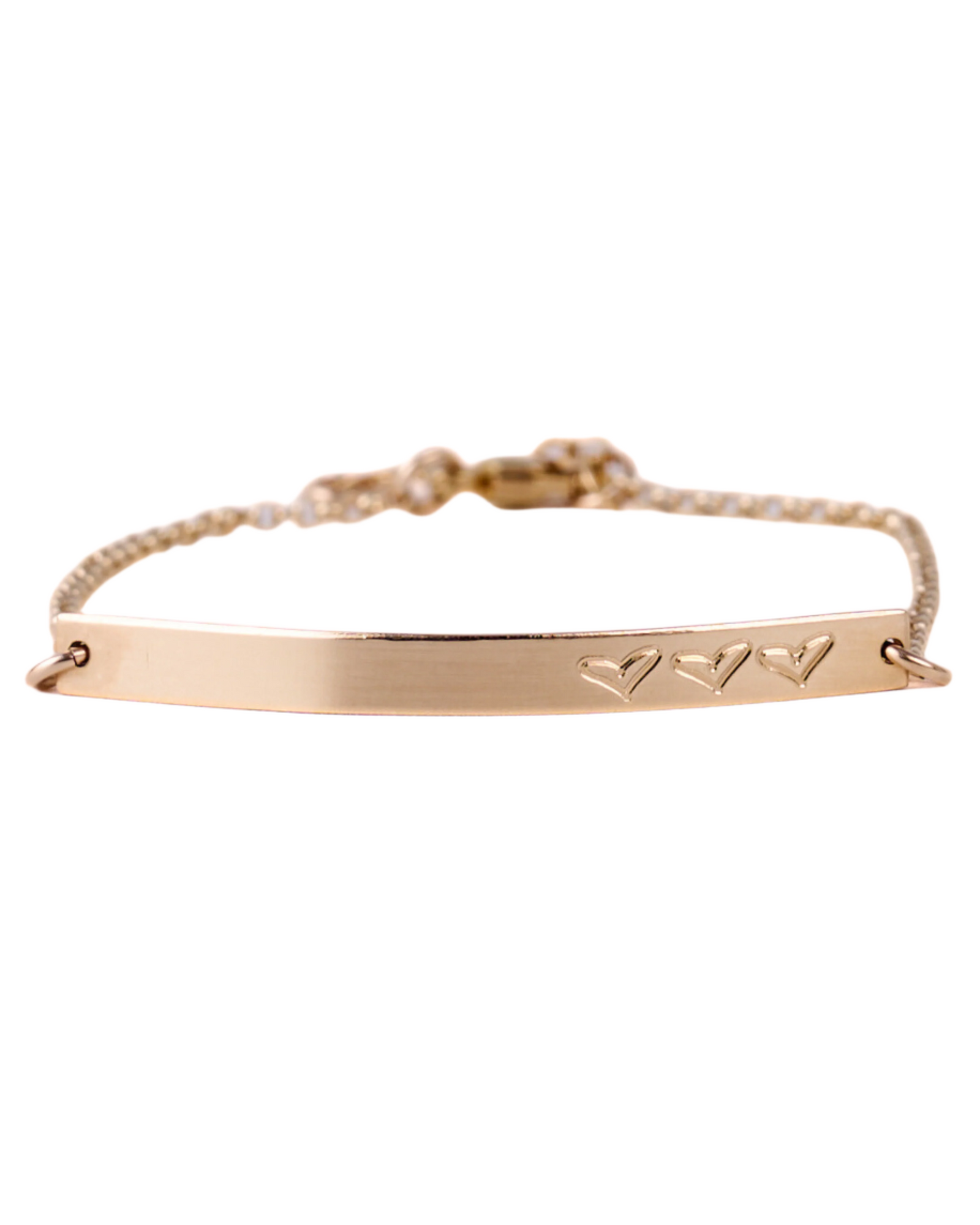 A gold-filled bracelet with a bar charm featuring engraved hearts, on a white background.