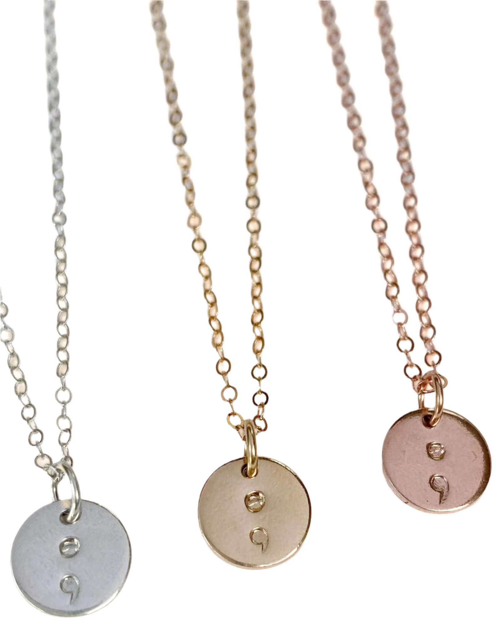 A collection of three semicolon necklace pendants on chains, in silver, gold, and rose gold colors.