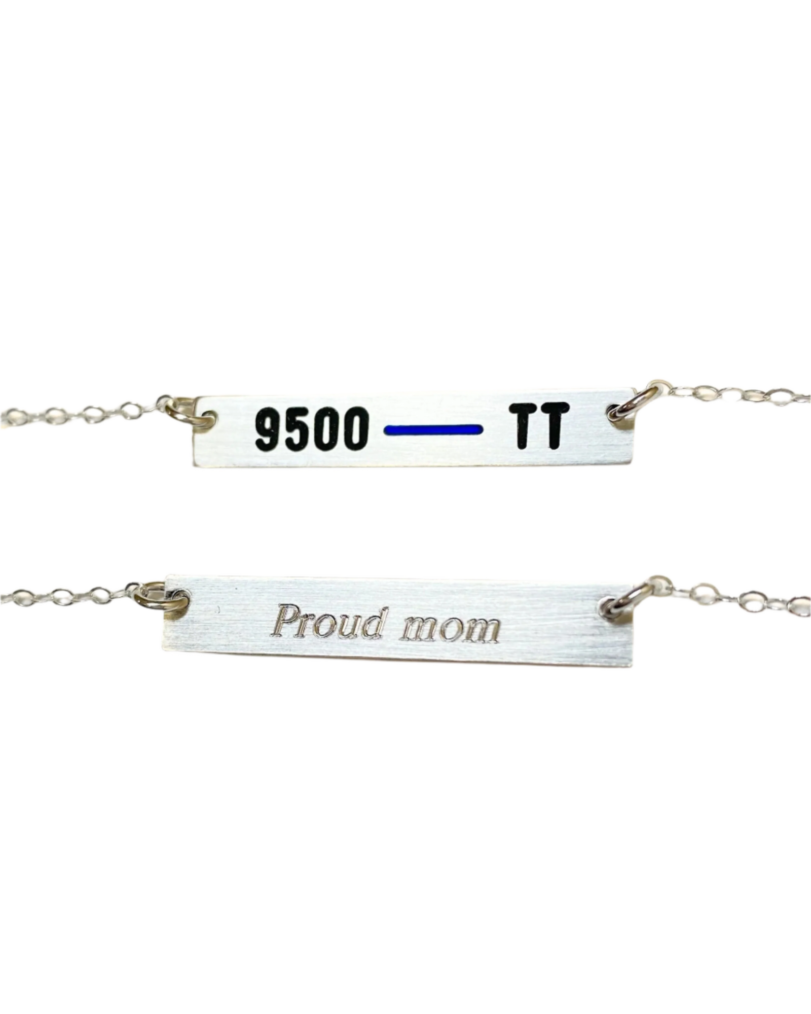 A silver necklace with a horizontal bar pendant engraved with '9500 TT' on one side and 'Proud mom' on the other, attached to a chain.