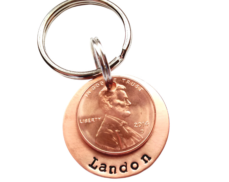 A copper keychain with a stamped message and a personalized penny charm displaying the name 'Landon'.